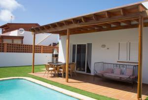 un patio con una piscina, una mesa y una casa en Villa Taginaste en Corralejo