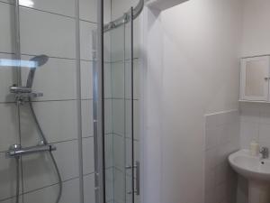 a bathroom with a glass shower with a sink at Soft & Bright in Thornton Heath