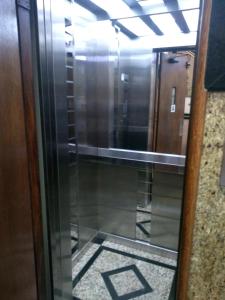a glass door with a reflection of a elevator at Hotel Macabu in Barra Mansa