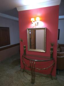 a red wall in a room with a mirror at Hotel Macabu in Barra Mansa