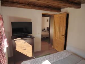 a bedroom with a television and a dresser with a bed at Oma's Hutte in Cărpiniş