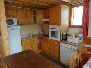 a kitchen with wooden cabinets and a white refrigerator at Les Adrets 1 Isola 2000 in Isola 2000