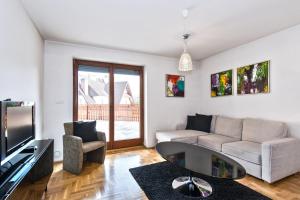 a living room with a couch and a tv at Apartamenty Sun & Snow Pardałówka in Zakopane