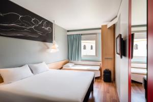 a bedroom with a large bed and a large window at Ibis Sevilla in Seville