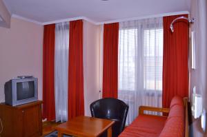 a living room with a couch and a tv and a table at Hotel Drama Burgas in Burgas