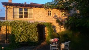 a brick house with two chairs and flowers in front of it at Casa Colli Piacentini in Pianello Val Tidone