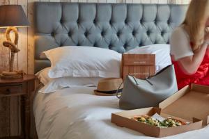 a girl is sitting on a bed with a pizza in a box at Lulworth Lodge in Lulworth Cove