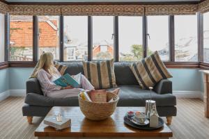a woman sitting on a couch reading a book at Lulworth Lodge in Lulworth Cove