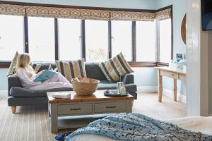 a girl sitting on a couch in a living room at Lulworth Lodge in Lulworth Cove