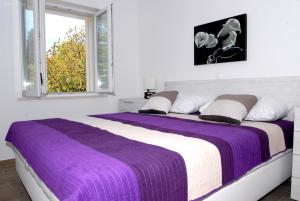 a bedroom with a purple and white bed with a window at Villa Mambo in Mlini