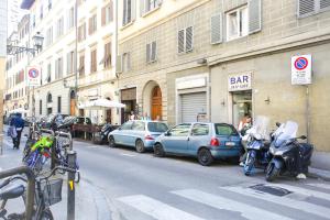 a street with cars and motorcycles parked next to a building at Via Guelfa Apartment in Florence