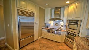 a kitchen with white cabinets and a stainless steel refrigerator at Portofino House in South Padre Island