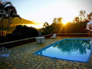 a swimming pool with a sunset in the background at Chacara na Serra da Mantiqueira in Santo Antônio do Pinhal