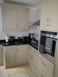 a kitchen with white cabinets and a stove top oven at Wherstead Road House in Ipswich