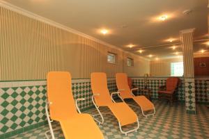 une salle d'attente avec des chaises orange et du carrelage vert et blanc dans l'établissement Hotel Appartement Landhaus Stutzi - Hotel Strandperle, à Cuxhaven