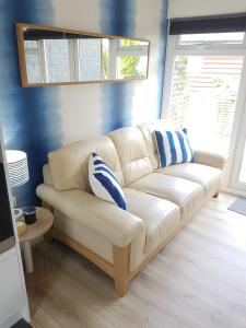 a white couch with blue pillows in a living room at Cabin 246 Riverside, Glan Gwna in Caeathro