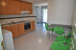 a kitchen with a table and green chairs in it at Nikitas Apartment in Kos