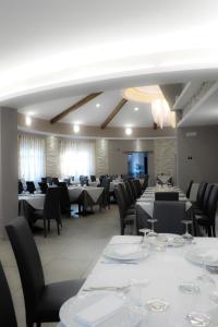 una sala da pranzo con tavoli bianchi e sedie nere di Hotel Duca Di Calabria a Serra San Bruno