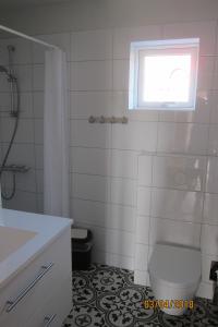 a white bathroom with a toilet and a window at Reynivellir II in Gerdi