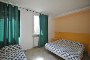 a bedroom with a bed and a window with green curtains at Villa Fiorella in Castiglioncello