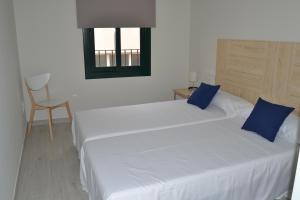 カンブリルスにあるApartamento Trempatのベッドルーム1室(白いベッド2台、青い枕付)