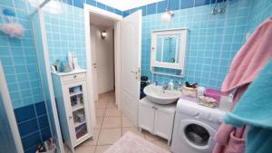 een blauwe badkamer met een wastafel en een wasmachine bij Vicino al mare nel cuore di Santa Teresa Gallura in Santa Teresa Gallura