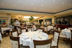 un restaurante con mesas y sillas blancas y gente en Duni Pelican Hotel - All Inclusive, en Sozopol