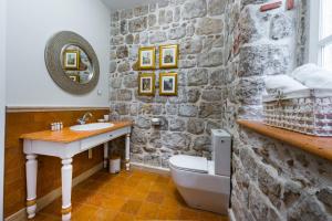 a bathroom with a stone wall and a sink and a toilet at Dominus Rooms in Dubrovnik