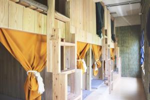 - une rangée de lits superposés dans un dortoir doté de rideaux jaunes dans l'établissement Guesthouse Asibina, à Ishigaki