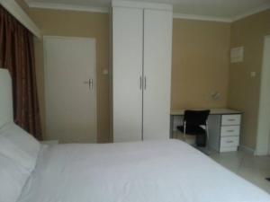 Nora Valley Lodge في Ruwa: غرفة نوم مع سرير أبيض كبير ومكتب