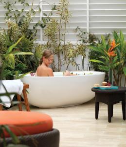 una mujer sentada en una bañera rodeada de plantas en L'Auberge Del Mar Resort and Spa, en San Diego