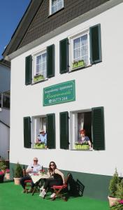 eine Gruppe von Menschen, die vor einem Gebäude an einem Tisch sitzen in der Unterkunft Rheinpromenade in Kamp-Bornhofen