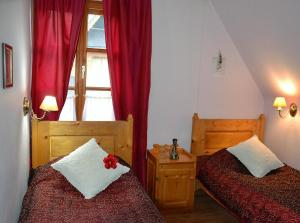 a bedroom with two beds and a window with red curtains at Willa Alta in Bukowina Tatrzańska