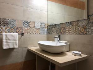 un bagno con lavandino bianco e piastrelle sul muro di B&B MiMì a Porto Cesareo