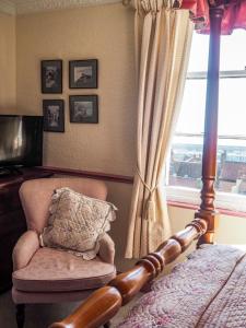 a bedroom with a bed and a chair and a window at Tall Storeys in Scarborough