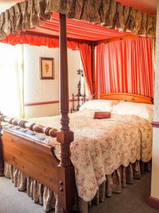 a bedroom with a four poster bed with red curtains at Tall Storeys in Scarborough