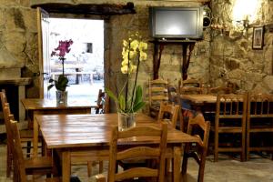 jadalnia ze stołami i telewizorem na kamiennej ścianie w obiekcie Iberik Casa Vilamor w mieście Vilamor