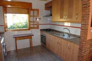 cocina con armarios de madera, fregadero y ventana en Fuente de la Yedra, en Arroyo Frío