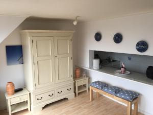 a room with a large white cabinet and two benches at Sylter Ferienwohnungen in Westerland
