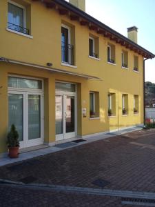 un bâtiment jaune avec des portes coulissantes dans une rue en briques dans l'établissement Hotel C25, à Ponzano Veneto