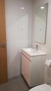 een witte badkamer met een wastafel en een spiegel bij Beira Rio do Gerês in Geres