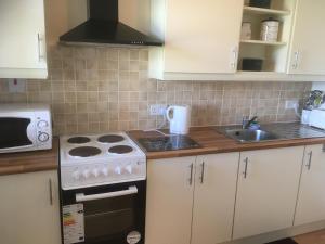 a kitchen with white cabinets and a stove and a sink at Baurleigh studio apartment P72F340 in Lissaphooca Cross Roads