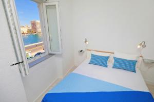 a bedroom with a bed with blue and white pillows and a window at Sea View Studio Apartment in Zadar