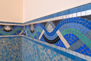 a tiled bathroom with a blue and white tile wall at La Maison Rouge Brocéliande in Montauban-de-Bretagne