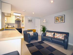 a kitchen and a living room with two blue leather chairs at 1 Fox Studios in Much Wenlock