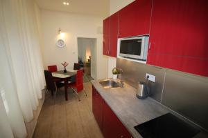 プラハにあるSmart City Prague Apartmentの小さなキッチン(赤いキャビネット、テーブル、テーブル付)