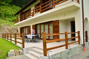 a man standing on the deck of a house at Pensiunea Valea Pinului in Rau Sadului
