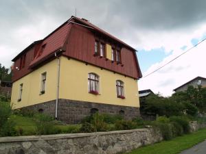 ein Haus mit einem roten Dach und einer Steinmauer in der Unterkunft U Nás in Smržovka
