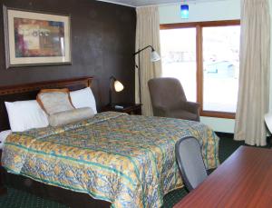 um quarto de hotel com uma cama e uma cadeira e uma janela em Budget Inn Palmyra em Palmyra