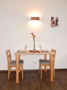 una mesa con dos sillas y un jarrón con flores. en ff Appartements, en Bramberg am Wildkogel